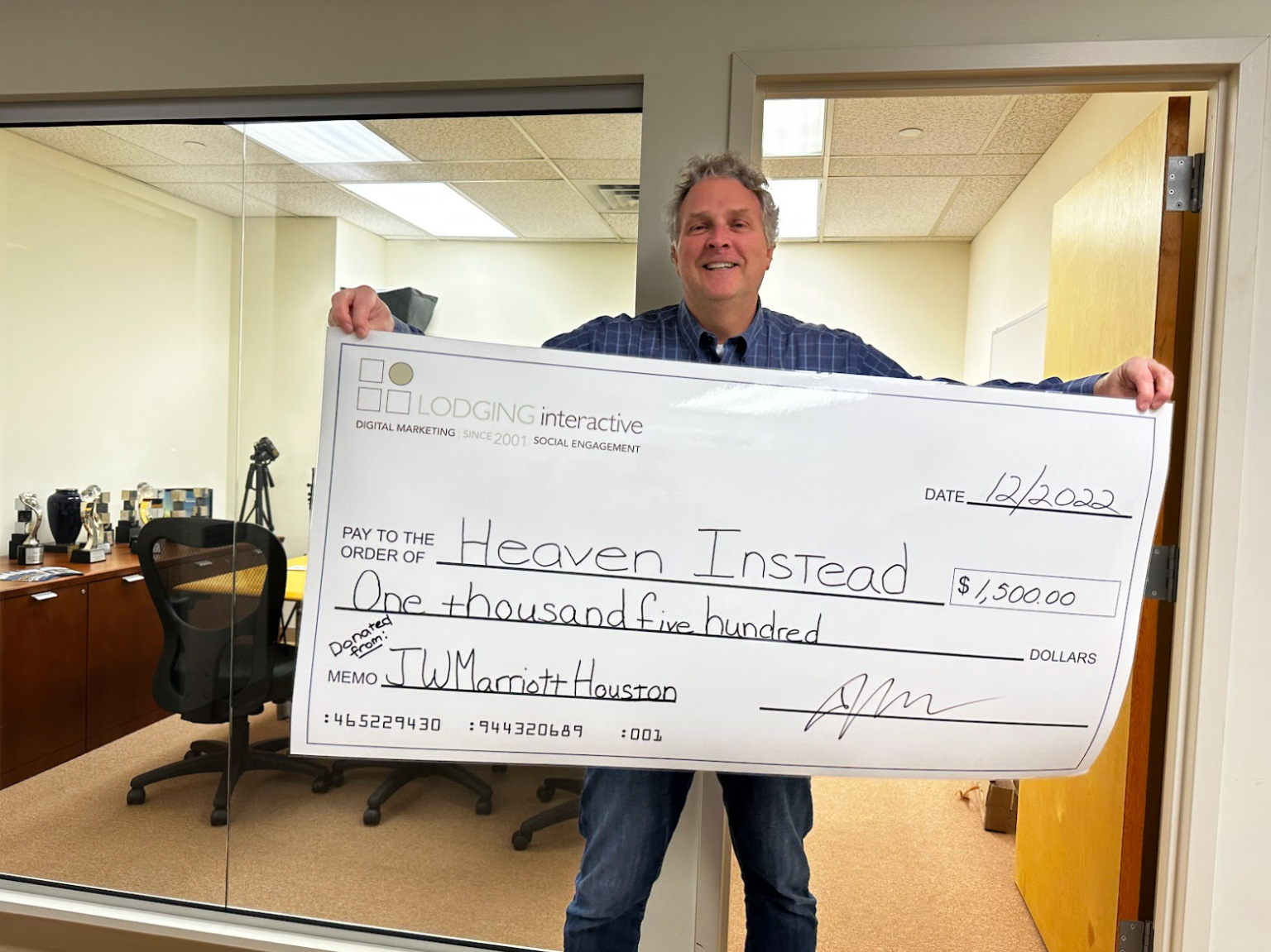 Lodging Interactive’s Founder & CEO holding the ceremonial check paid to Heaven Instead on behalf of the JW Marriott Houston Downtown Hotel.— Photo by Lodging Interactive